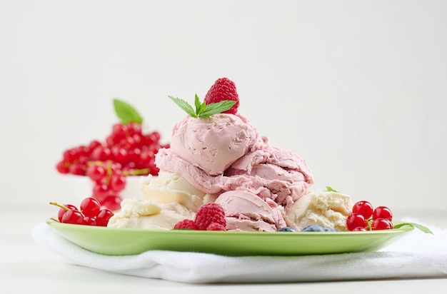 Vanilla and raspberry ice cream scoops on a round green plate