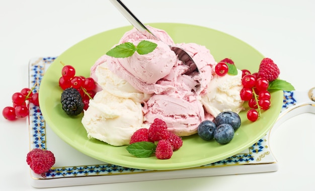 Vanilla and raspberry ice cream scoops on a round green plate