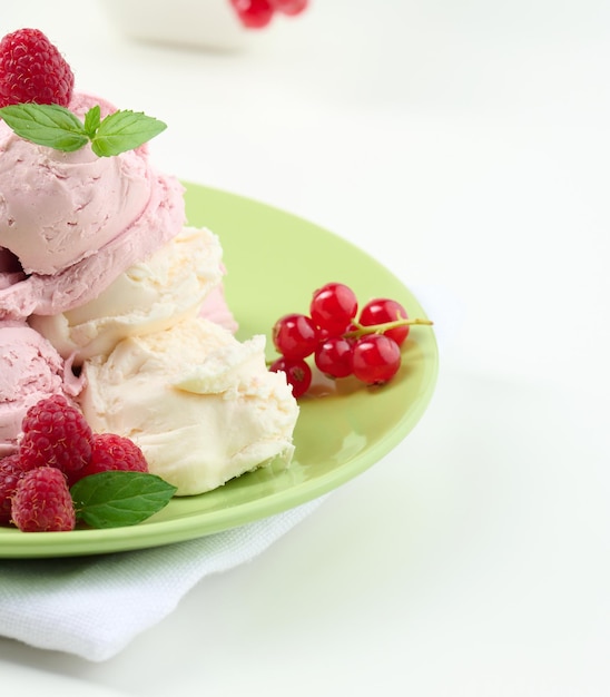 Vanilla and raspberry ice cream scoops on a round green plate