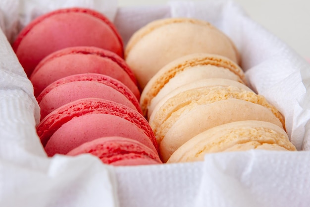 Vanilla and strawberry macaroons in a box on a white napkin a sweets