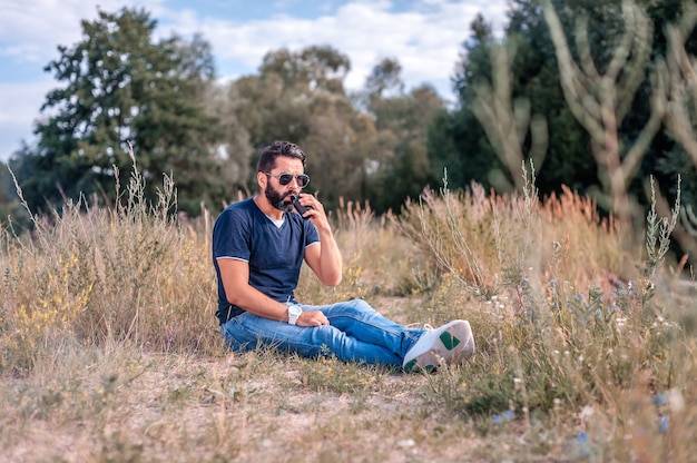 vape man hold and smoking his electronic smoke device blowing a stream of smoke spread