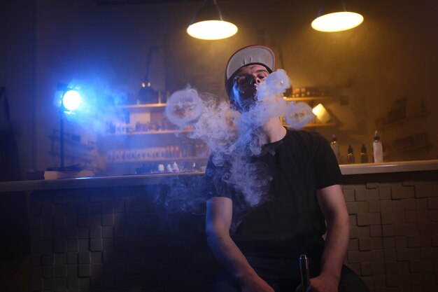 Vaping man in a cloud of vapor in a vape bar