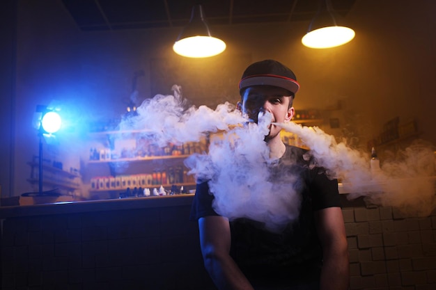 Vaping man holding a mod a cloud of vapor at the vape shop