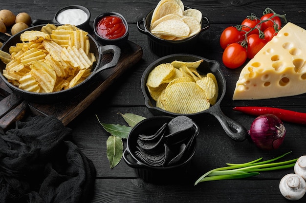 Variation different potato chips set on black wooden background