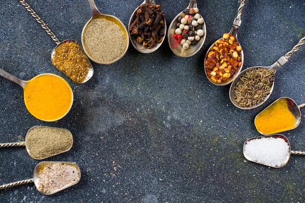 Variation of spices on the vintage silver spoons, all spices on the table, colorful food  