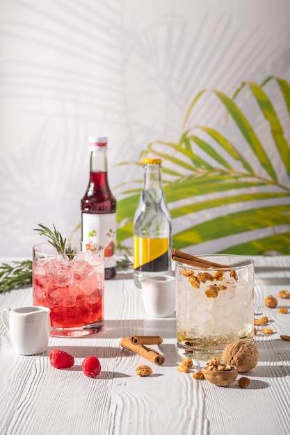 Variations of espresso-tonic refreshing drink with different fruits and syrups on wooden table under morning sun