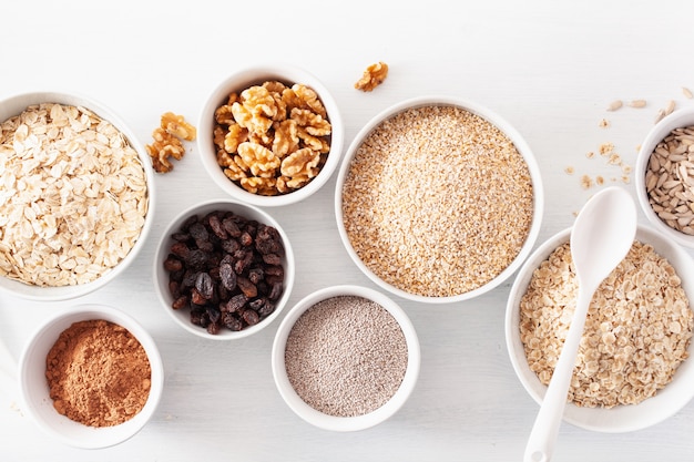 Variaty of raw cereals and nuts for breakfast. Oatmeal flakes and steel cut, barley, walnut, chia, raisins. Healthy ingredients