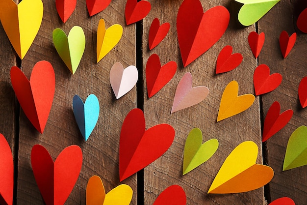 Varicolored paper hearts on wooden background close up