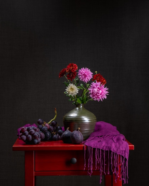 Variegated bouquet of autumn flowers Dahlias Dark background Still life with flowers and grapes and fresh figs Postcard Holiday Congratulations