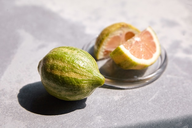 Variegated Eureka lemon  with striped rind in glass saucer on concrete table