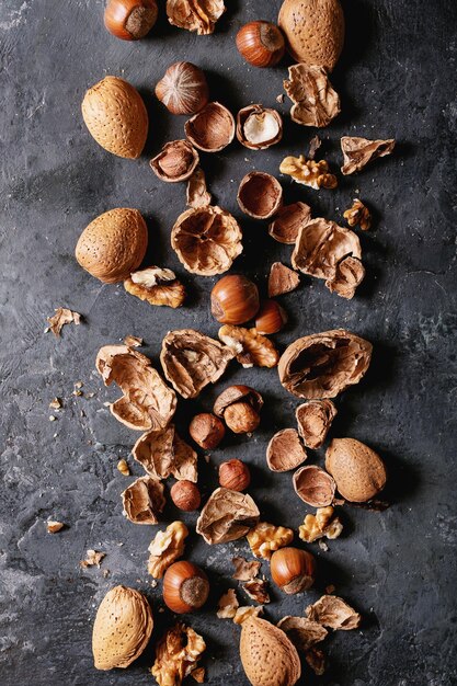 Varieties of nuts: almonds, hazelnuts and walnuts over dark texture background. Top view, flat lay. Copy space