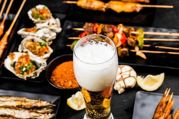 A variety of barbecue dishes and beer are placed on the black wooden background