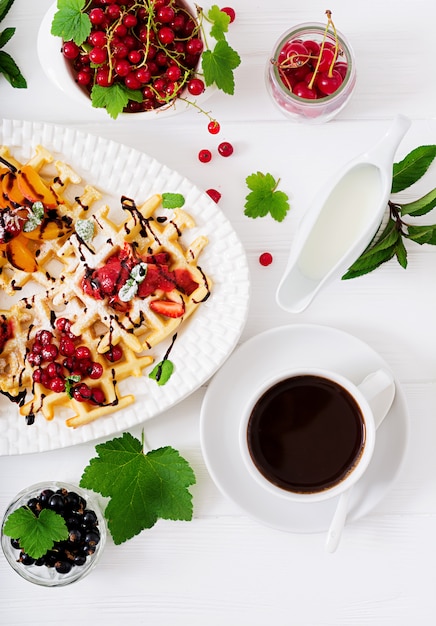 Variety of Belgian wafers with berries, chocolate and syrup.