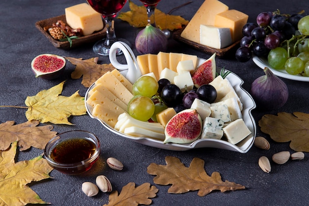 Variety of cheese and fruits on gray table. Appetizer for Thanksgiving Day.