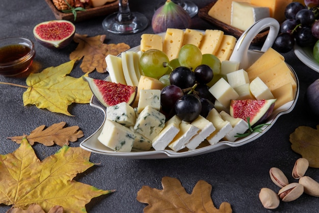 Variety of cheese nuts and fruits on gray table Appetizer for Thanksgiving Day