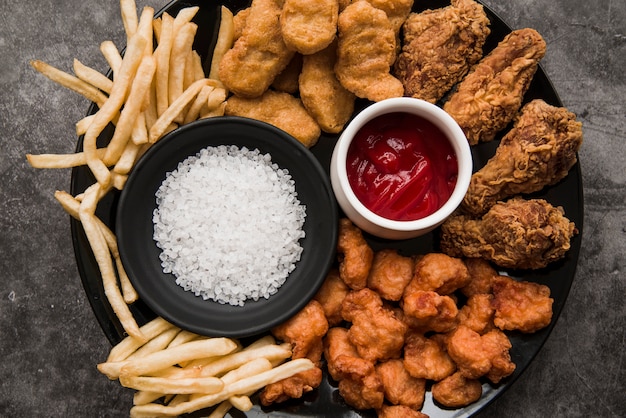 Variety of chicken dishes; french fries with salt and tomato sauce in plate