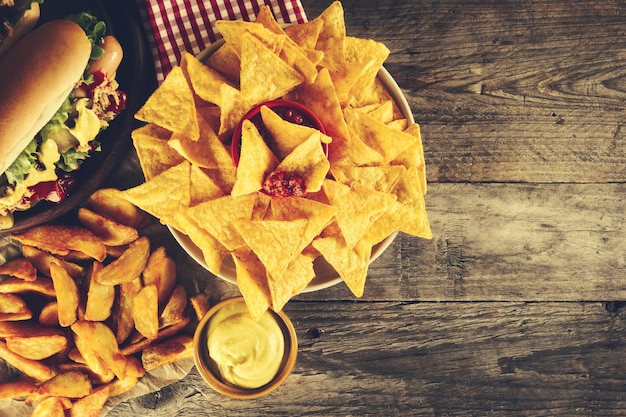 Variety of classic traditional american tasty junk unhealthy food on wooden background with copy space. Hot Dogs and Chips. Toning.