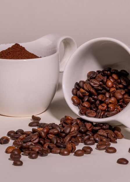 Variety of coffee Two porcelain white cups with coffee beans and ground coffee