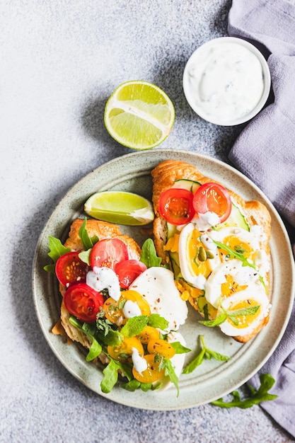 Variety of croissant sandwiches with tomato cucumber mozzarella eggs and avocado mint and arugula