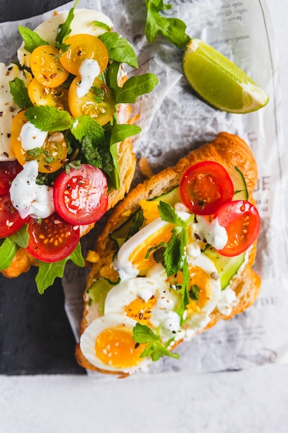 Variety of croissant sandwiches with tomato cucumber mozzarella eggs and avocado mint and arugula