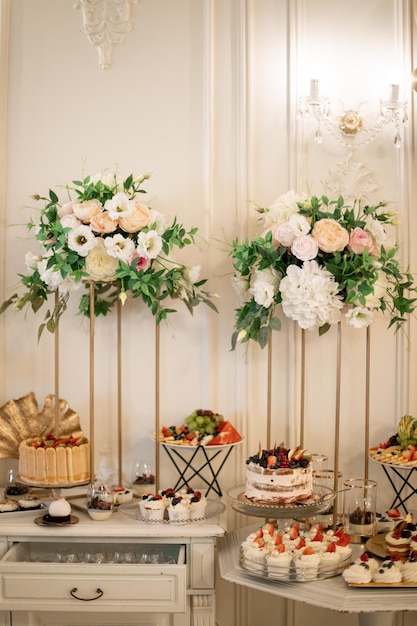 Variety of desserts with cream, nooses and fruits in restaurant in wedding with floristic decoration and luxury environment