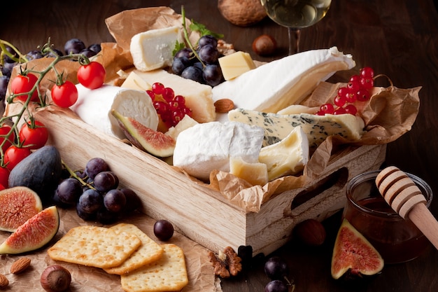 Variety of different cheese with wine, fruits and nuts. Camembert, goat cheese, roquefort, gorgonzolla, gauda, parmesan, emmental, brie