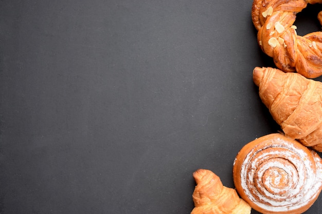 Variety of fresh baked buns on black board. Bakery background