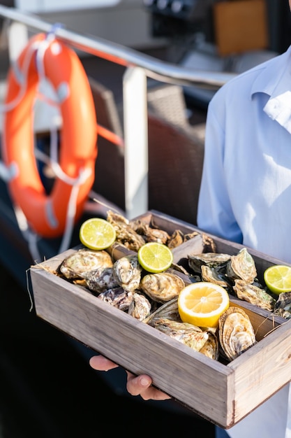 A variety of fresh oysters with lime and lemon in wooden box Fresh seafood Outdoor cafe terrace