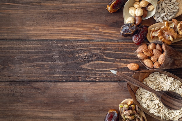 Variety of grains and mixed nuts in organic plates, on wooden brown background , top view with copy space