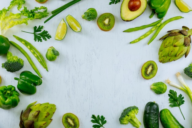 Variety of green vegetables and fruits on a wooden table top view workplace cook with fresh