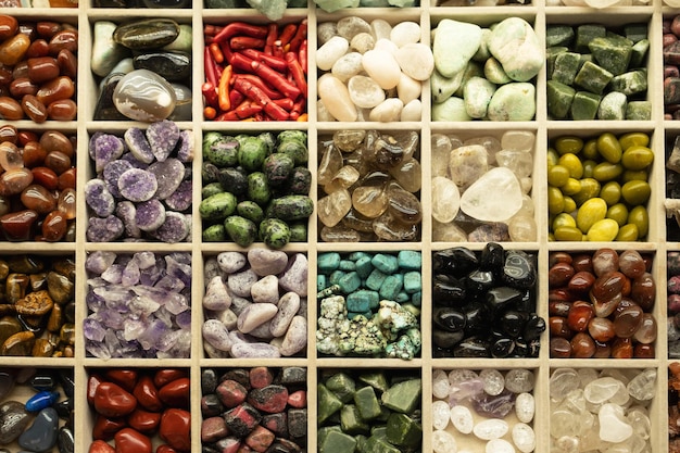 Variety of many beautiful colorful stonessmall rocks of different colors in wooden boxView from top Natural background