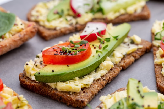 Variety of mini sandwiches with cream cheese, vegetables and salami.