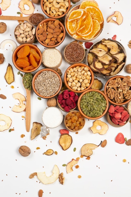 A variety of nuts and seeds are arranged in bowls on a white background.