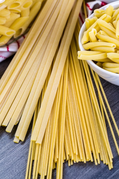 Variety of organic dry pasta on wood board.