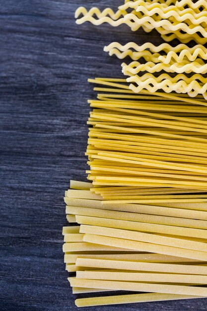 Variety of organic dry pasta on wood board.