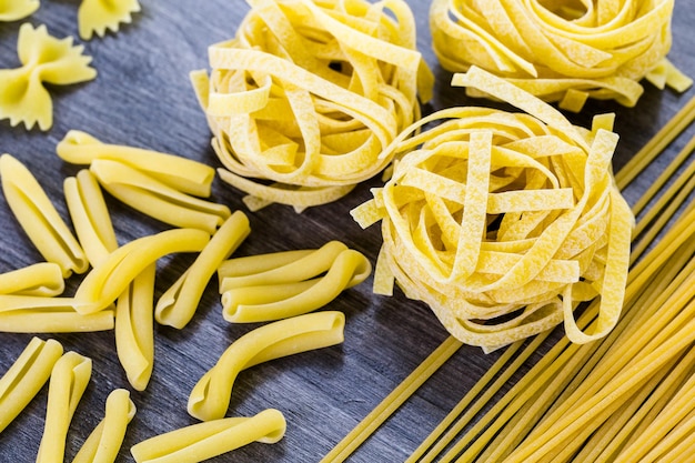 Variety of organic dry pasta on wood board.