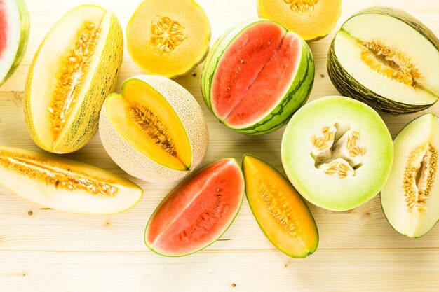 Variety of organic melons sliced on wood table.