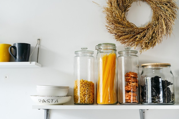 Variety of pasta in glass jars on a shelf on a white background Zero waste eco friendly package