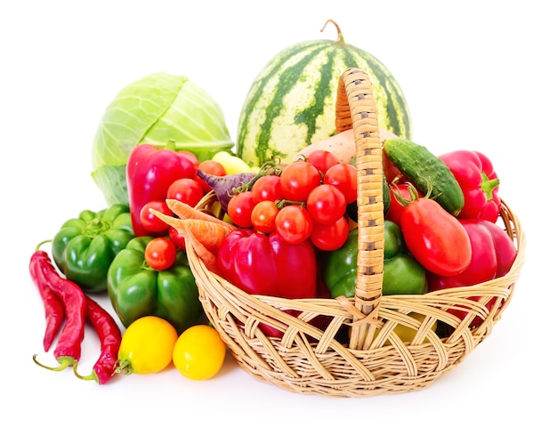 Variety of raw vegetables in wicker basket isolated on white.