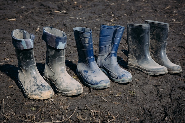 Variety of rubber boots in a line in the dirt in early spring