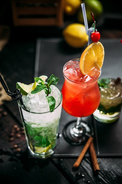 Variety of sweet alcohol coktails in different glasses, mojito, mai tai and sex on the beach, side view, vertical