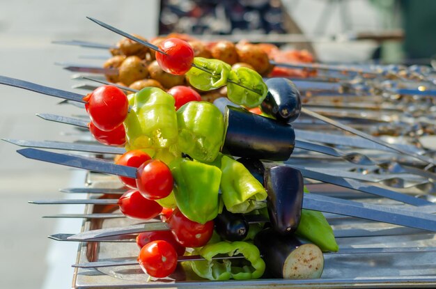 A variety of vegetables are on skewers on a grill.