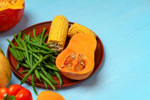 Variety of vegetables including pumpkins on blue pastel background