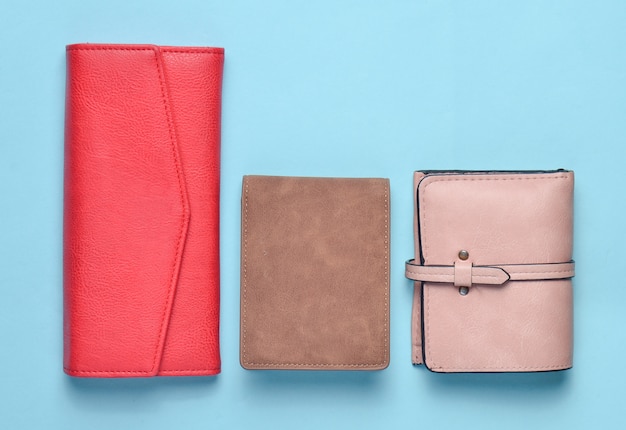 A variety of women's leather wallets on a blue pastel background, women's accessories, top view, minimalism