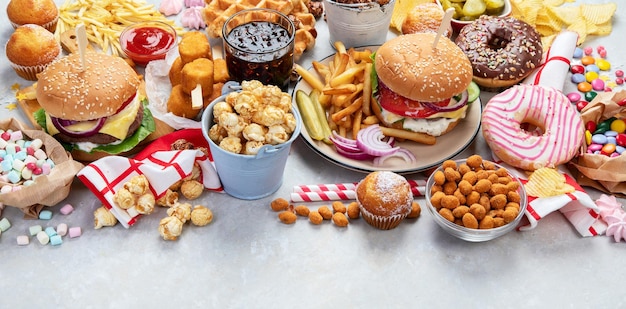 Various of american food French fries hamburgers nuggets hotdog chips popcorn sauces on a white background top view Panorama with copy space