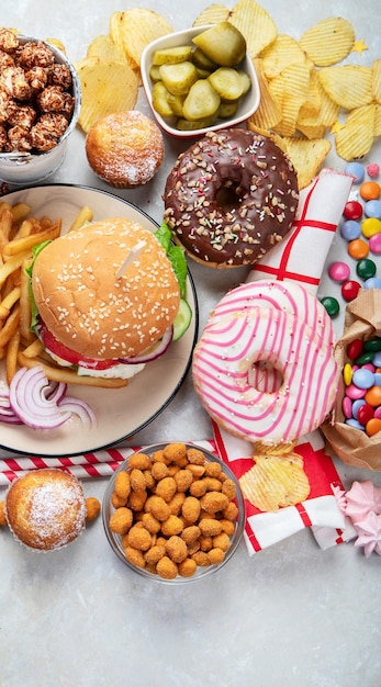 Various of american food French fries hamburgers nuggets hotdog chips popcorn sauces on a white background top view