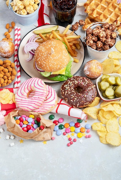 Various of american food French fries hamburgers nuggets hotdog chips popcorn sauces on a white background top view