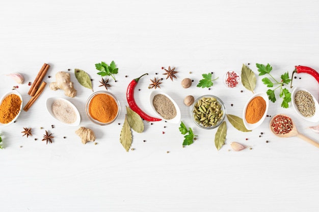 Various assorted colorful spices and herbs on white wooden background top view