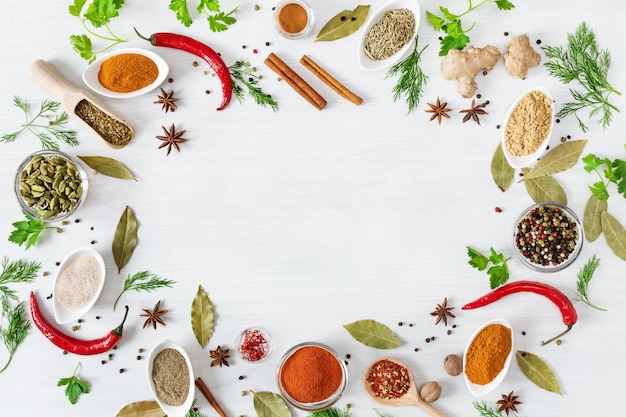 Various assorted colorful spices and herbs on white wooden background top view