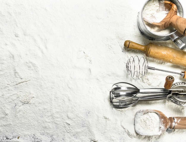 Various baking tools on flour. Top view